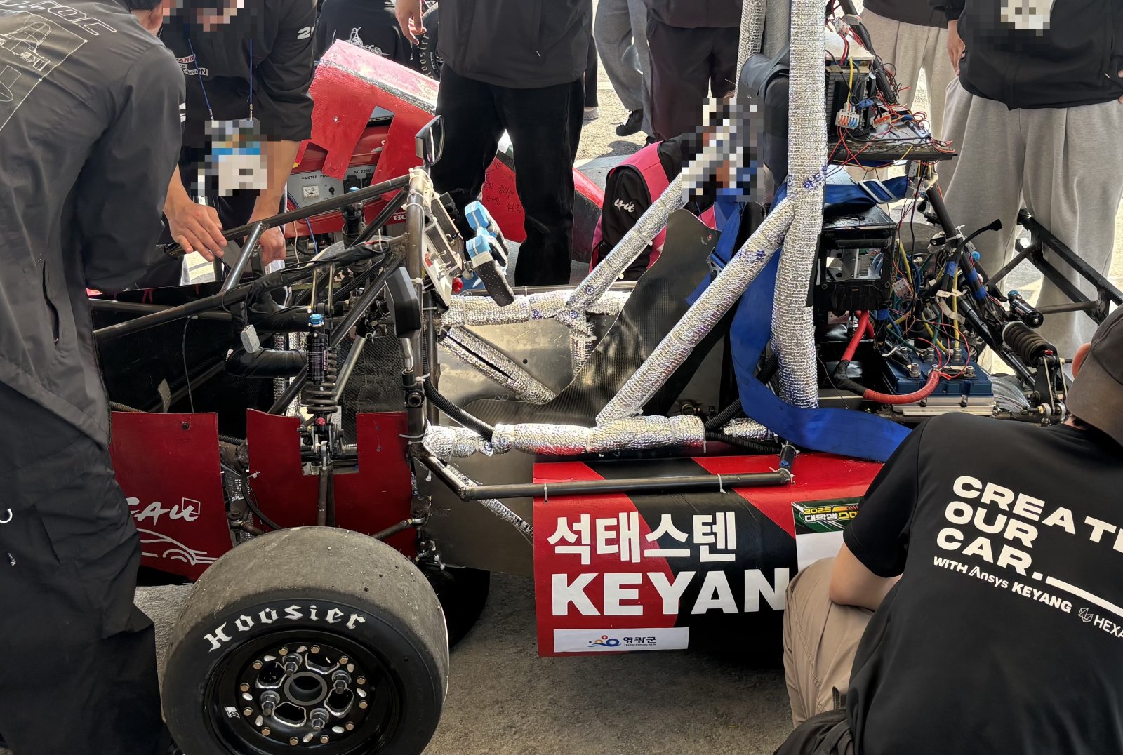 Student EV race car in the pit on day two, team diagnosing the water-cooled motor controller after the water pump stopped circulating coolant